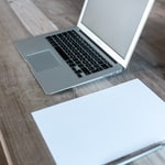 Teaser Content Management Schreibtischplatte aus Holz mit Laptop und weißem Blatt Papier